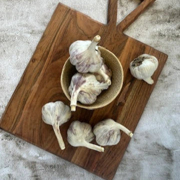 Garlic bulbs on a wooden cutting board and surface