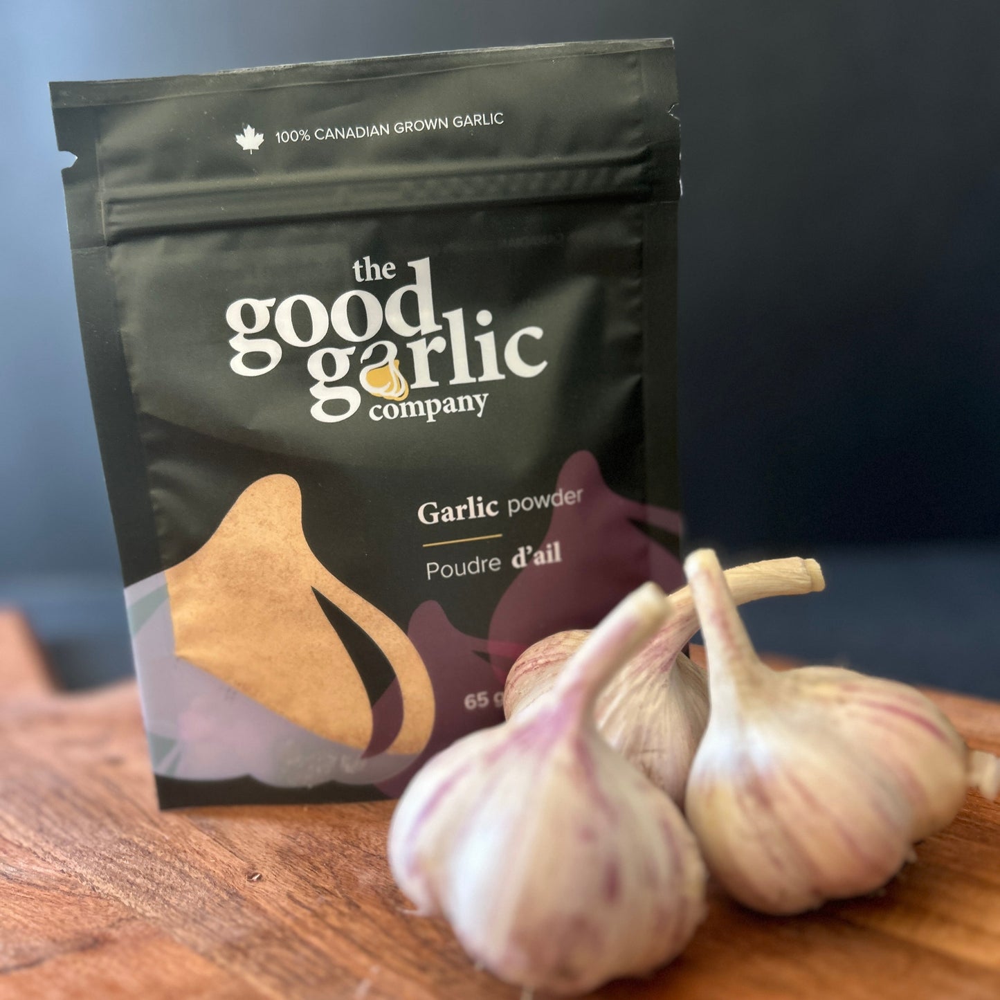 Garlic powder package from 'The Good Garlic Company' with three garlic bulbs on a wooden surface.